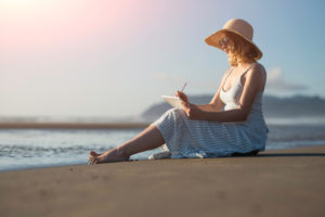 Lady writing sat on beach
